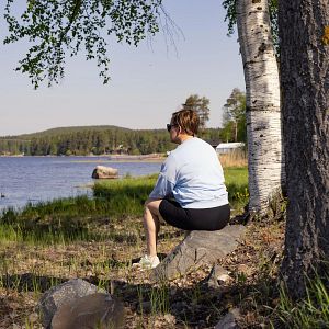 Nainen istuu kalliolla Vuorelan satamassa Siilinjärvellä veden äärellä.