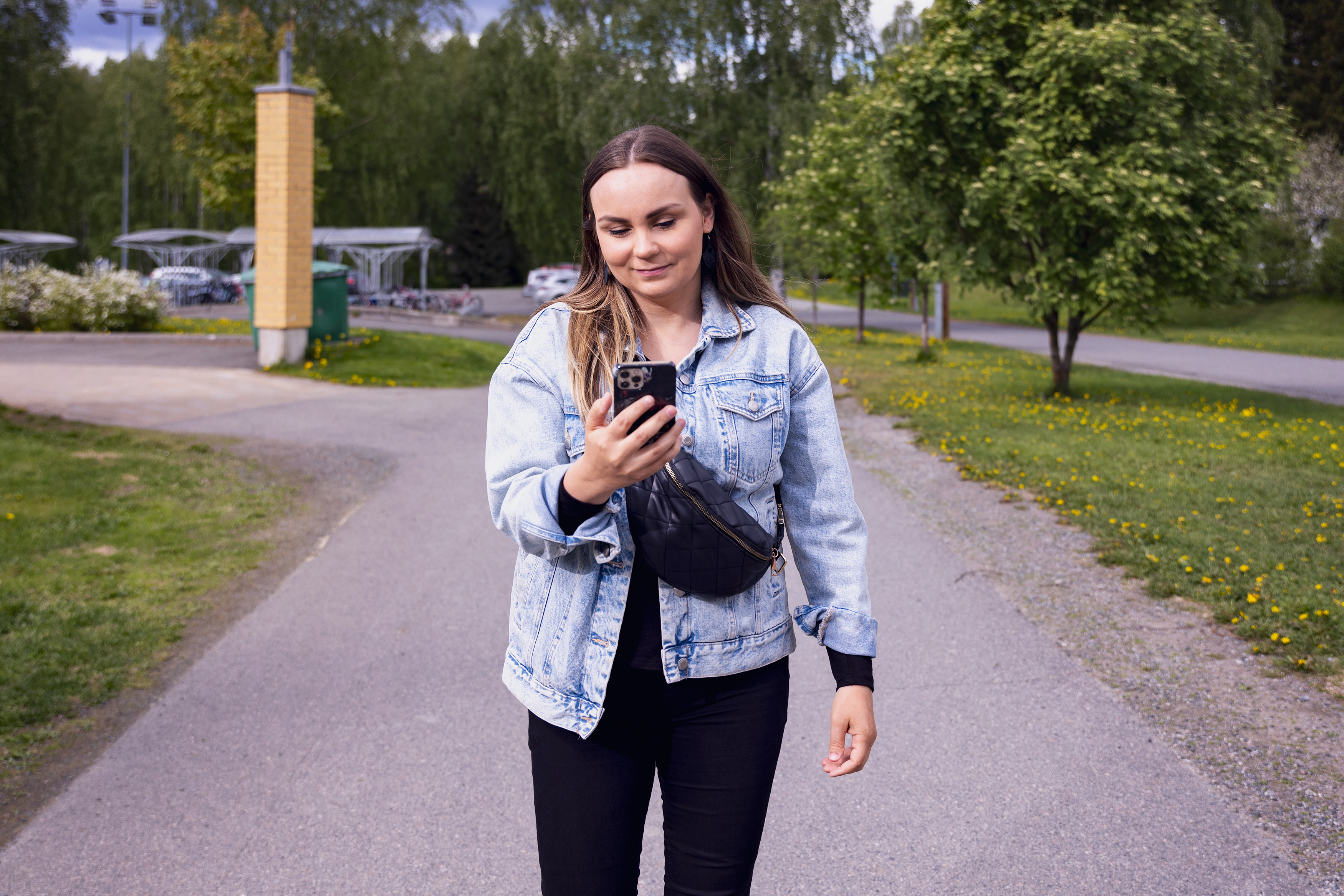 Kuvassa nainen katsoo matkapuhelinta.